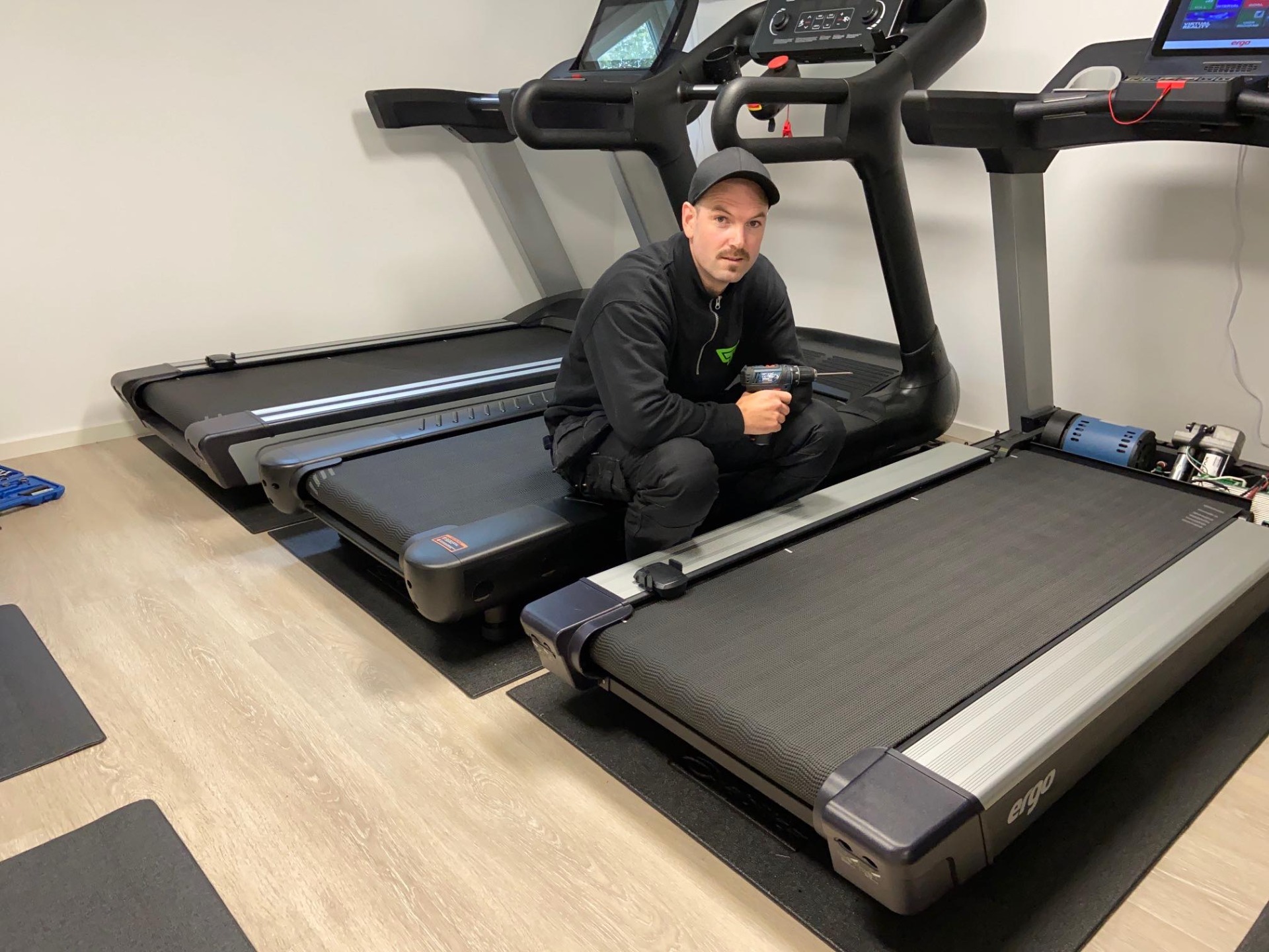 Servicetekniker fra TGA Service utfører vedlikehold på tredemølle i bedriftsgym.